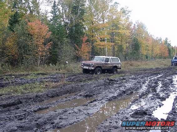 Brown 1978 Ford Bronco stuck in mud on a wooded trail