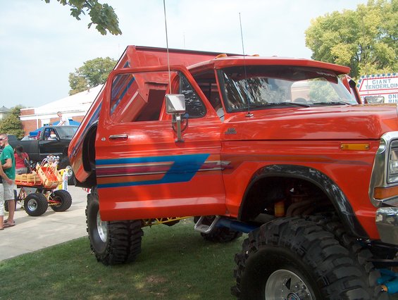 Orange lifted truck with dump bed and blue stripe graphics