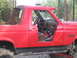 1989 Ford Bronco - The interior of a red 1989 Ford Bronco is visible through the open driver's side door, revealing the dashboard and seats.