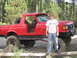 1989 Ford Bronco - Red 1989 Ford Bronco parked off-road with a young person standing next to it.