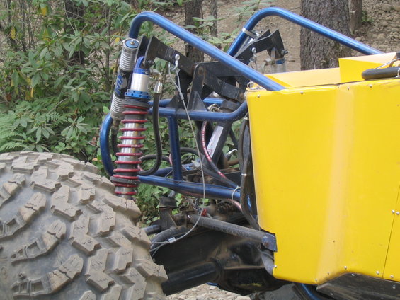Off-road vehicle rear tire and blue suspension system with yellow body panel