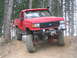 1989 Ford Bronco - Modified red Ford truck with large off-road tires navigates a steep dirt path.