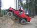 1989 Ford Bronco - A red off-road SUV navigates a steep dirt incline in a wooded area.