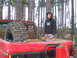 1989 Ford Bronco - A person stands next to a red pickup truck loaded with a spare tire and a gas can, in a wooded area.