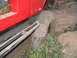 1989 Ford Bronco - A red off-road vehicle navigates a challenging terrain, with its tire pressed against a fallen log.
