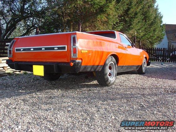 Orange 1974 Ford Ranchero with black bumper and tailgate panel, parked on gravel