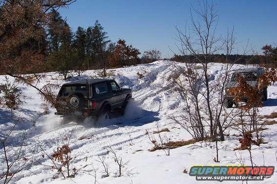 1978 Ford Bronco and another SUV driving on a snowy hill