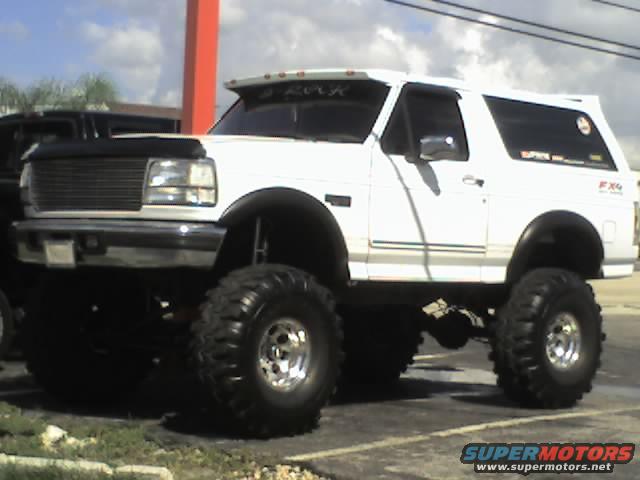 Lifted white 1995 Ford Bronco with large off-road tires, side view