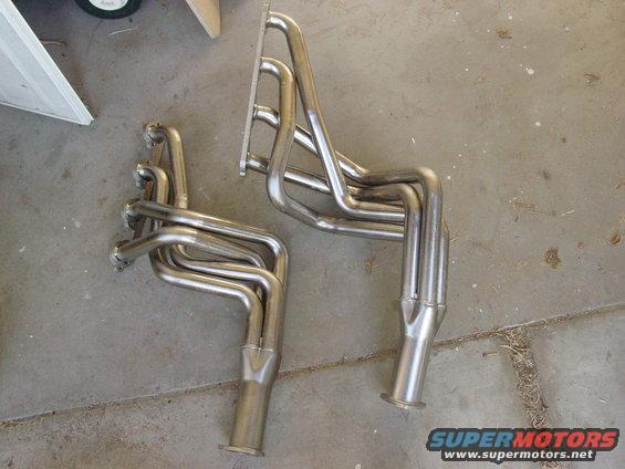 Two stainless steel exhaust headers on a concrete floor