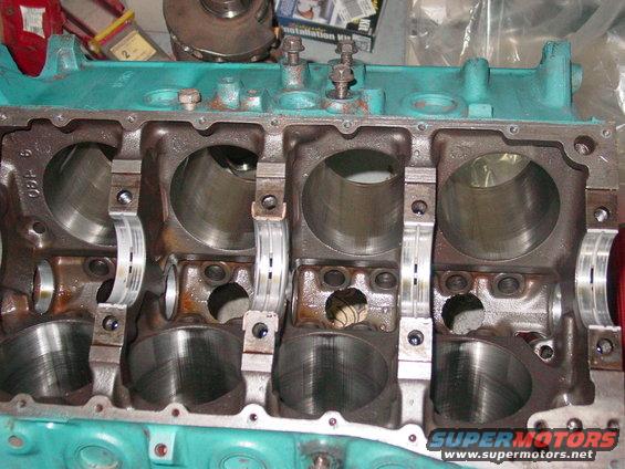 Teal engine block with four cylinders and crankshaft bearings visible