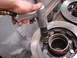 1989 Ford Bronco - Close-up of a mechanic using an impact wrench on a vehicle's brake rotor assembly.