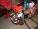 1989 Ford Bronco - Custom brake upgrade on a vehicle's rear axle, showing a new red caliper and rotor assembly.