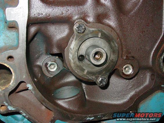 Close-up of a metal engine component with bolts and a central shaft