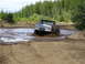 1989 Ford Bronco - Ford Bronco navigates a muddy off-road course, kicking up water and dirt.