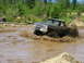 1989 Ford Bronco - A black 1979 Ford F-Series pickup truck navigates a muddy obstacle course, kicking up a large spray.