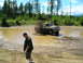 1989 Ford Bronco - A man watches a Ford pickup truck churn through a muddy off-road course, creating a large plume of dark exhaust.