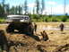 1989 Ford Bronco - A heavily modified truck navigates a muddy obstacle course with two onlookers nearby.