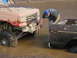 1989 Ford Bronco - A man inspects two off-road vehicles submerged in muddy water, one appearing to be a 1989 Ford Bronco.