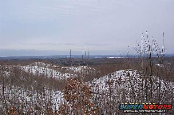 snowy hills and bare trees under a cloudy sky