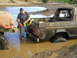 1989 Ford Bronco - A man attempts to tow a mud-covered 1978 Ford Bronco out of a muddy water hole.