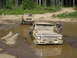 1989 Ford Bronco - A man cleans the windshield of a mud-splattered pickup truck stuck in a muddy puddle, with another truck behind it.
