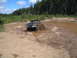 1989 Ford Bronco - A black Ford pickup truck navigates a muddy obstacle course in a wooded area.