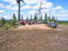 1989 Ford Bronco - A group of off-road vehicles and people are gathered in a muddy clearing surrounded by trees.