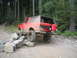 1989 Ford Bronco - This red SUV is navigating a rocky obstacle on a wooded trail, its off-road capabilities.