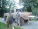1989 Ford Bronco - A muddy, lifted Ford F-Series pickup truck is parked on a gravel driveway with two men beside it.