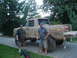 1989 Ford Bronco - Two men stand beside a heavily muddied 1979 Ford F-Series pickup truck, likely after off-road use.