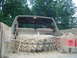 1989 Ford Bronco - The rear interior and cargo area of a mud-covered 1980s Ford Bronco, equipped with a spare tire and red gas cans.