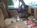 1989 Ford Bronco - The interior of a 1989 Ford Bronco is covered in mud, with stickers adorning the center console and a red steering wheel cover visible.