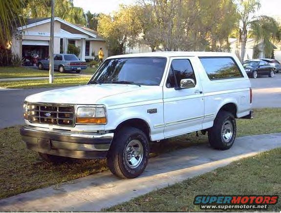 1995 Ford Bronco parked on a lawn in front of a house