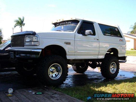 White 1995 Ford Bronco lifted with large tires, parked outdoors