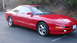 1996 Ford Probe - A red Ford Probe GT is parked in a lot with trees in the background.