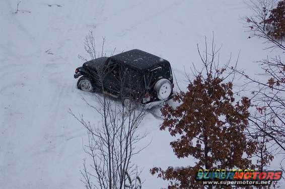 Black SUV with spare tire on rear, stuck in snow