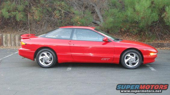 Red 1996 Ford Probe GT coupe parked on asphalt, side view. The car has a spoiler and alloy wheels