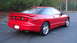 1996 Ford Probe - This red 1996 Ford Probe is shown from the rear 3/4 angle, a prominent spoiler and chrome wheels.