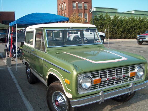 Green 1978 Ford Bronco with white top and hood stripe, front 3/4 view