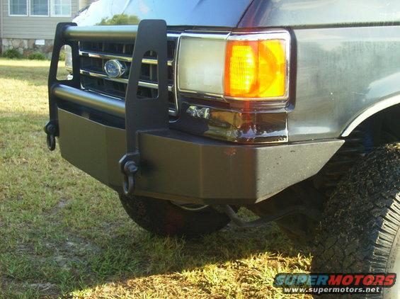 Dark gray Ford Bronco front bumper with brush guard and tow hooks. Visible "4x4" badge