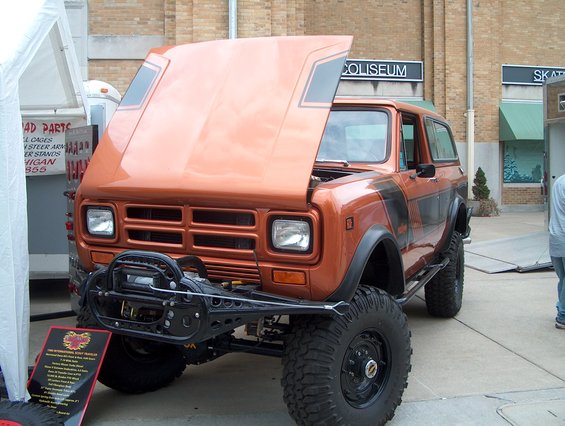 Orange International Scout II with hood open, black racing stripes, and winch bumper