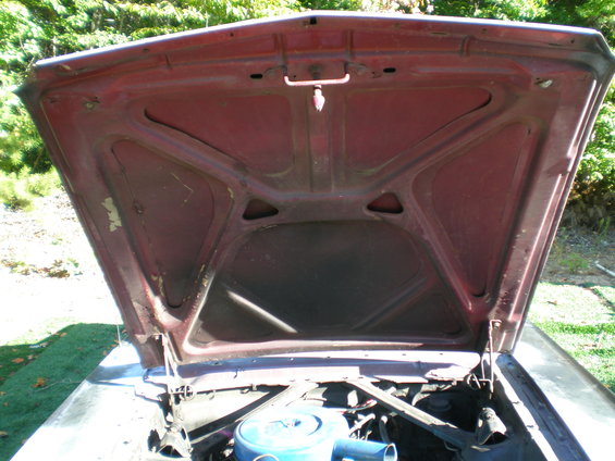 Red 1966 Ford Mustang hood interior with visible latch mechanism and engine components