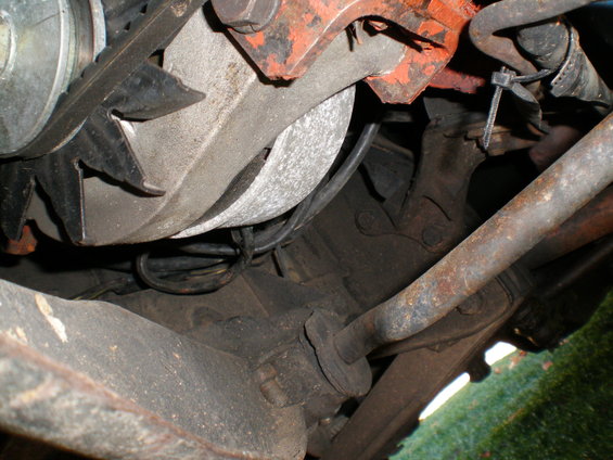 Close-up of alternator and engine parts, showing belt and wiring