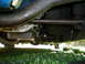1966 Ford Mustang - The underside of a vehicle shows a transmission pan and oily mechanical parts.