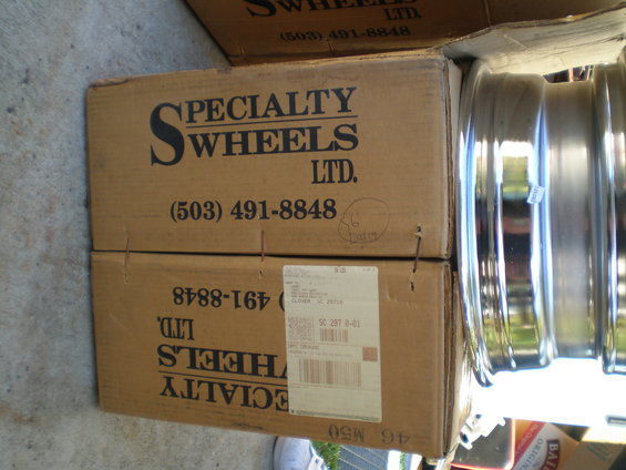 Two cardboard boxes labeled 'SPECIALTY WHEELS LTD.' with phone number (503) 491-8848, stacked next to chrome wheels