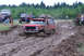 1989 Ford Bronco - Several off-road vehicles navigate a muddy track under a cloudy sky.