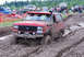 1989 Ford Bronco - Red 1989 Ford Bronco stuck in mud during a bogging event, with spectators and other vehicles nearby.