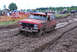 1989 Ford Bronco - A red Ford Bronco navigates a muddy track during an off-road event.