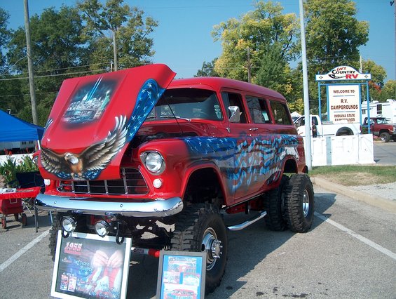 Red 1955 Chevrolet Suburban with patriotic airbrush art, lifted with large tires. Hood is open showing more art
