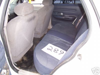 Interior rear seats of a white car, with a paper showing '289' on the seat